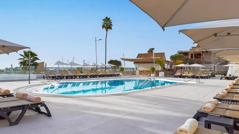 Terrasse avec piscine et transats sous des parasols.