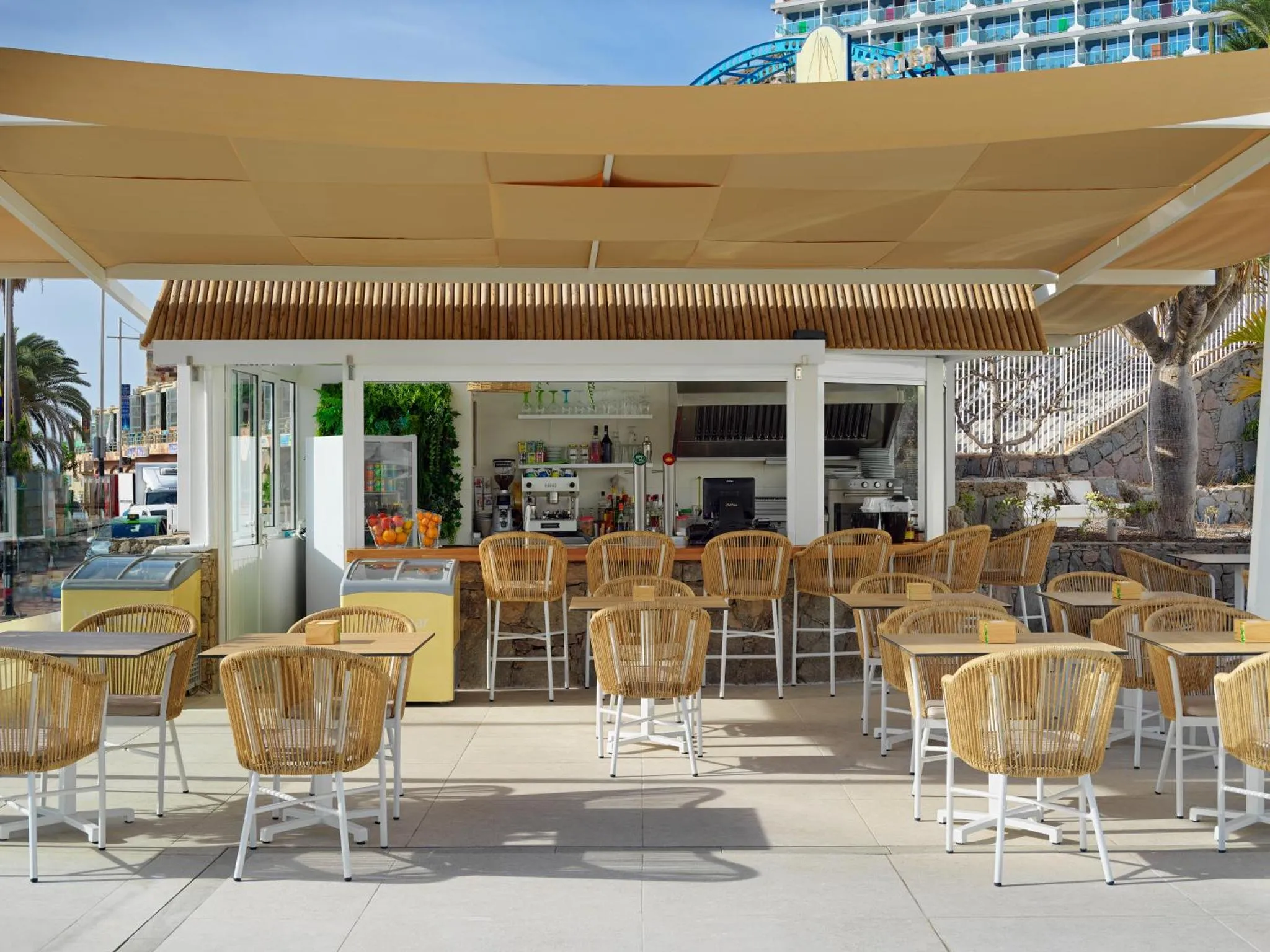 Terrasse ombragée avec un comptoir de bar et des tables.