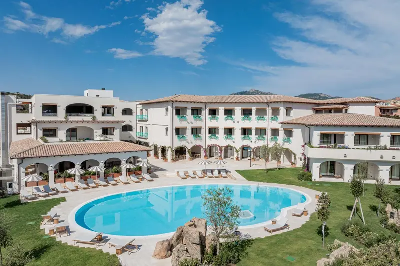 Vue aérienne d'un complexe hôtelier blanc avec une piscine et des transats.