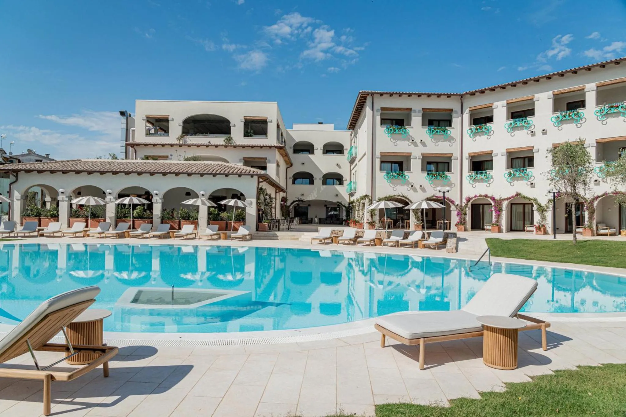 Bâtiment blanc avec des transats au bord d'une piscine bleu turquoise.
