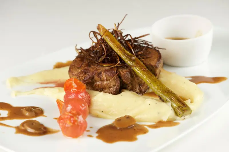 Assiette de viande accompagnée de purée et de légumes.