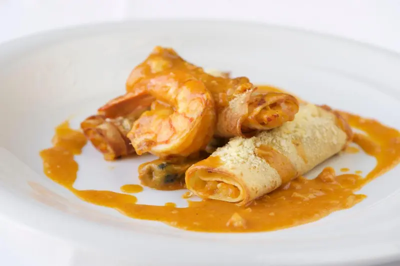 Assiette de crevettes enrobées de pâte, nappées d'une sauce orangée.