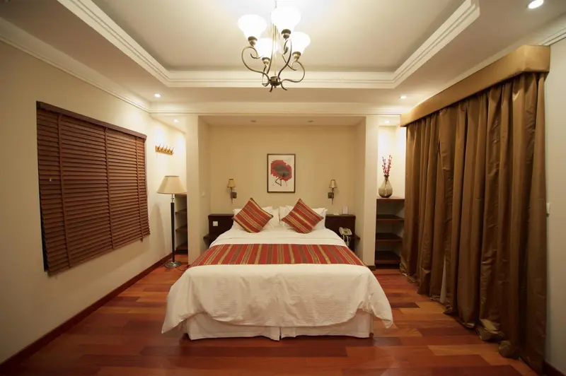 Une chambre lumineuse avec un grand lit et un parquet en bois.