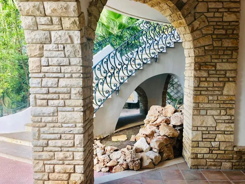 Escalier en pierre orné de fer forgé dans un décor extérieur.