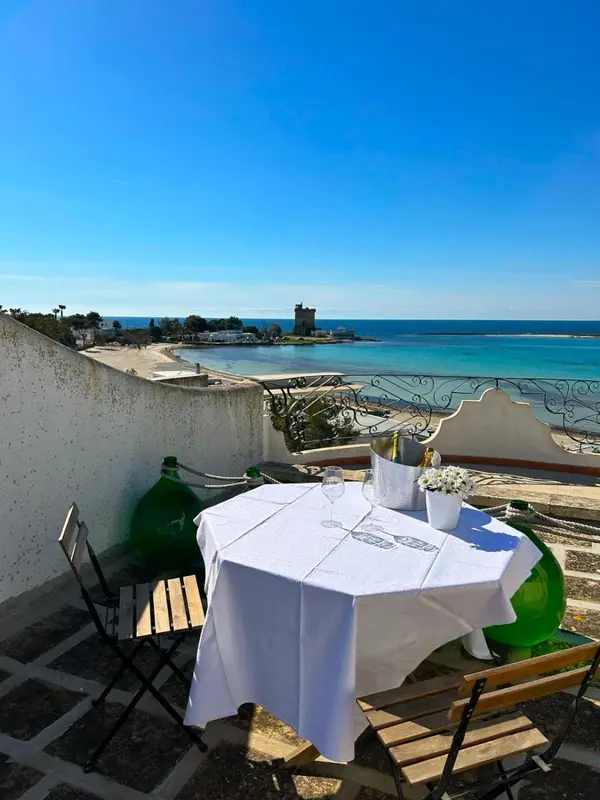Une table dressée sur une terrasse offre une vue sur la mer et la côte.