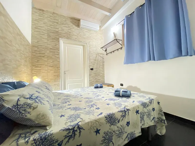 Une chambre lumineuse avec un lit recouvert d'une couette à motifs marins.