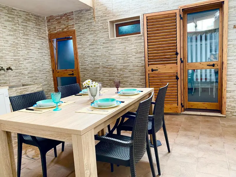 Une table à manger est mise en scène sur une terrasse carrelée.