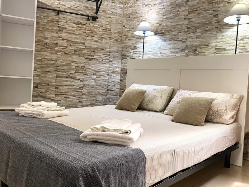 Lit double avec oreillers et couvertures dans une chambre décorée de pierres.
