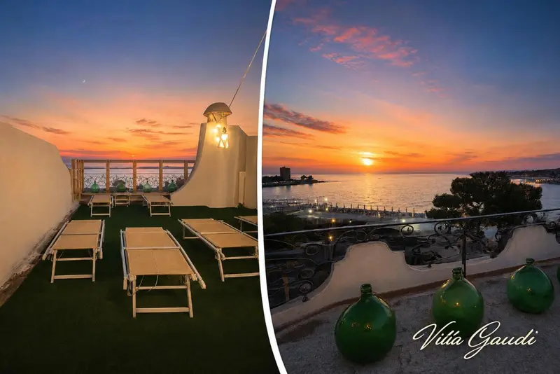 Terrasse avec chaises longues face à un coucher de soleil sur la mer.