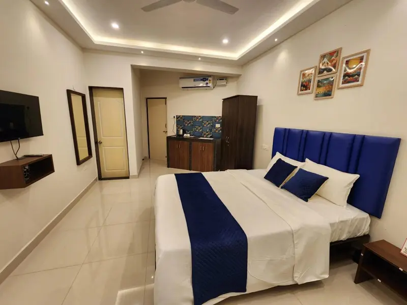 Une chambre lumineuse avec un grand lit et un espace cuisine.