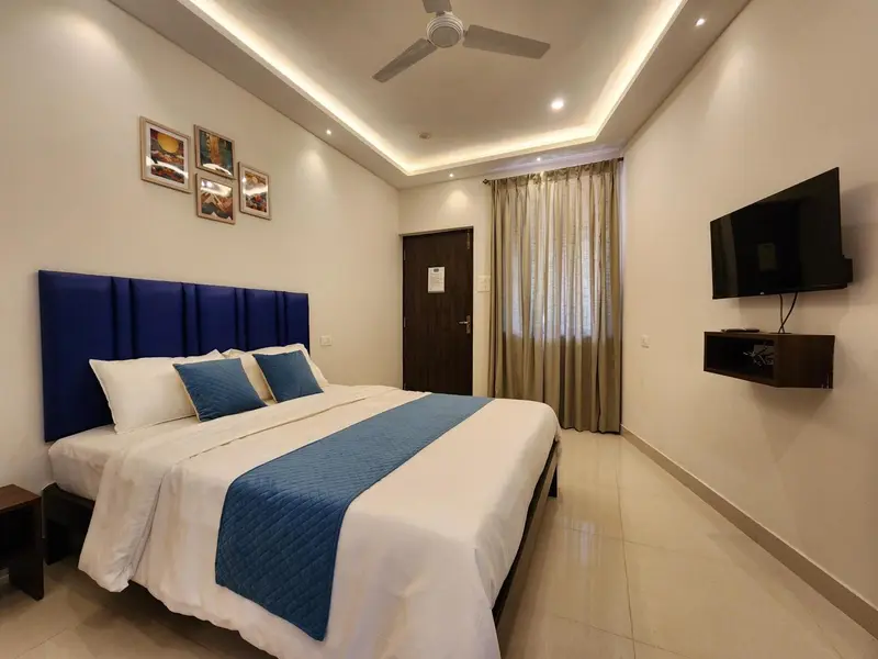 Une chambre lumineuse avec un grand lit recouvert d'une courtepointe bleue.