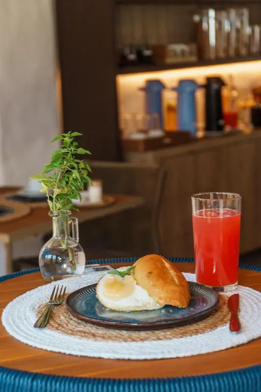 Un petit-déjeuner avec un sandwich et un jus de fruits est présenté sur une table.