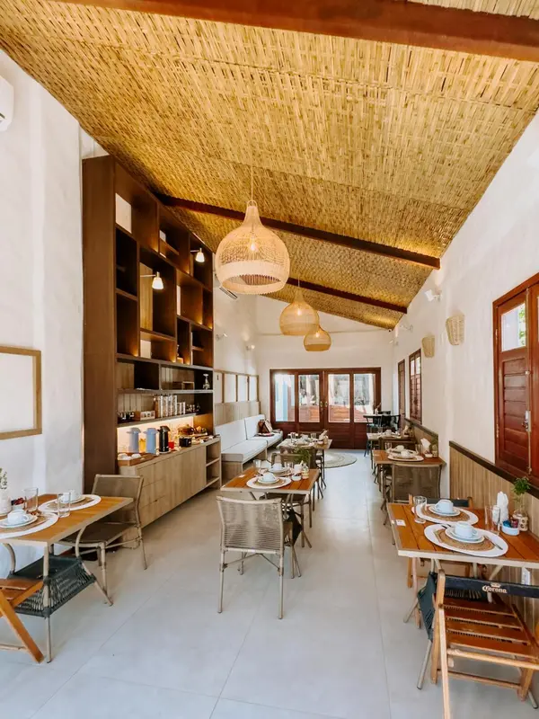 Une salle lumineuse avec des tables dressées pour le repas.
