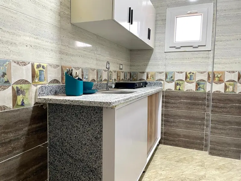Une kitchenette moderne avec un plan de travail en marbre et des armoires blanches.