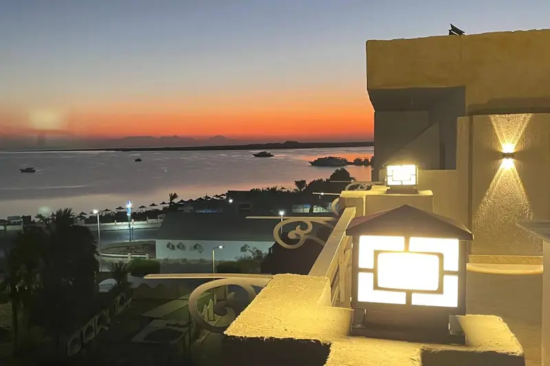 Coucher de soleil sur la mer avec une vue sur un complexe hôtelier.