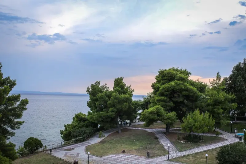 Vue d'un jardin verdoyant surplombant la mer au coucher du soleil.