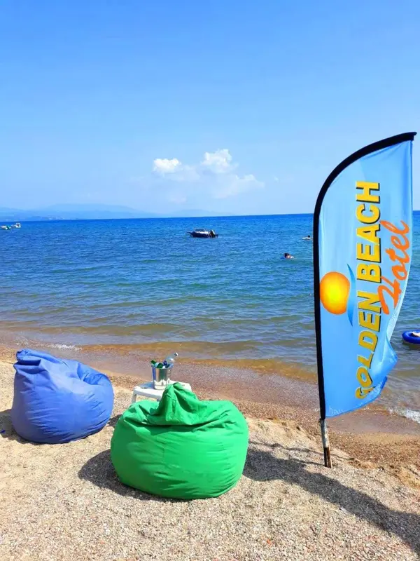 Plage de sable avec des fauteuils confortables et un drapeau publicitaire.