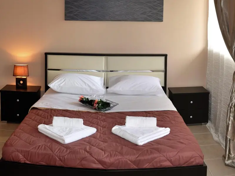 Une chambre avec un grand lit recouvert d'une courtepointe et de coussins.
