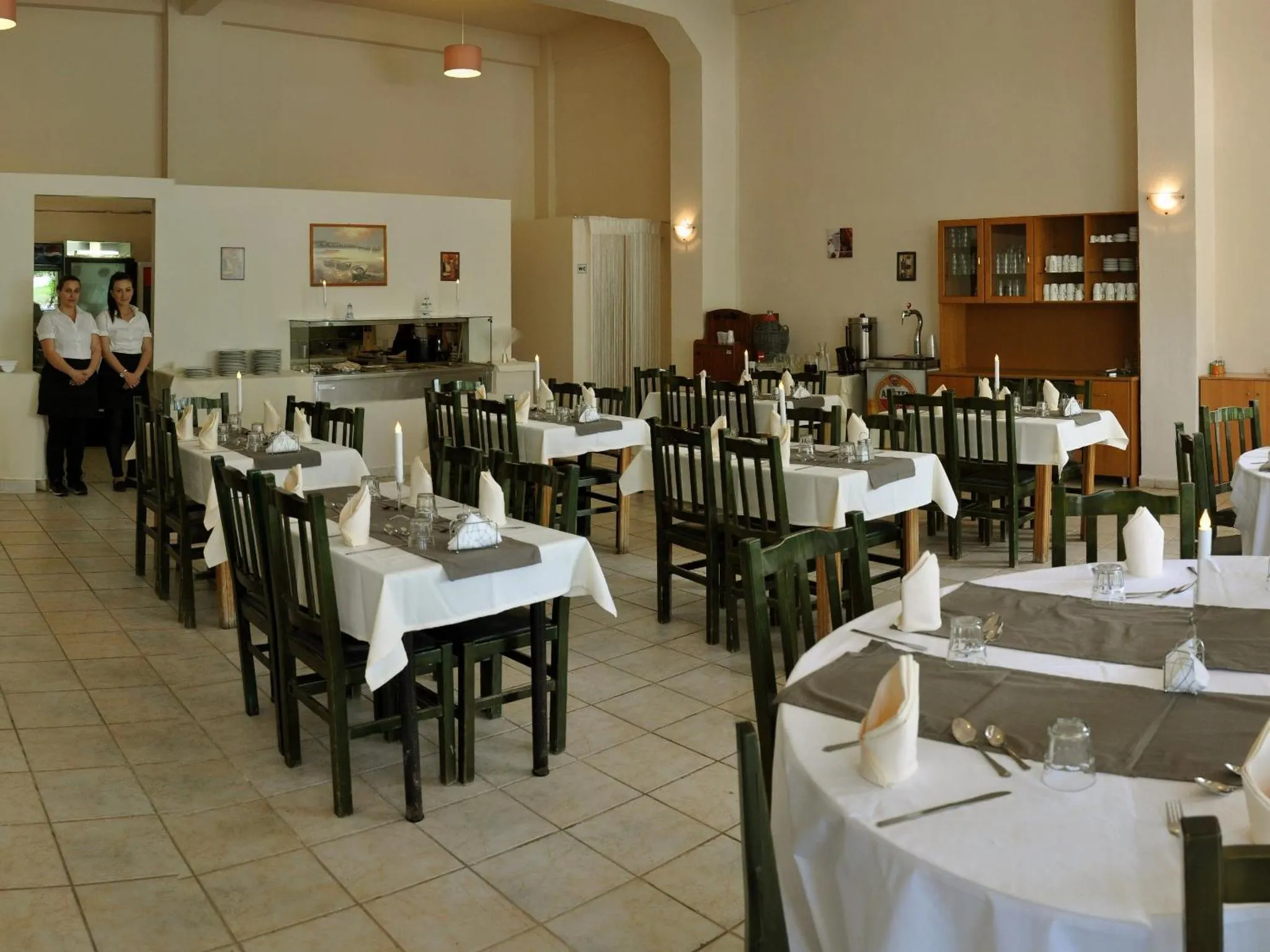 Une salle lumineuse avec des tables dressées pour le service.