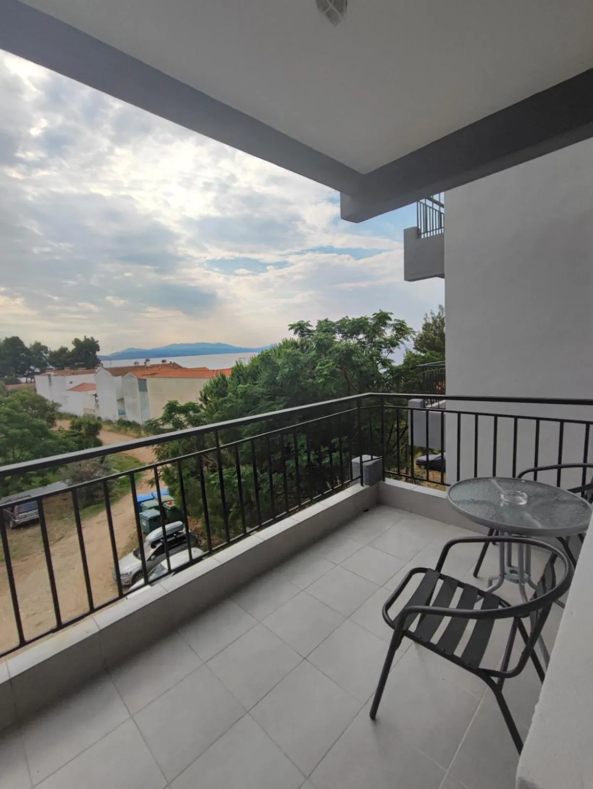 Terrasse carrelée avec mobilier de jardin et vue sur la mer.