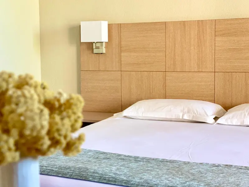 Un lit double avec des oreillers blancs et une tête de lit en bois clair.