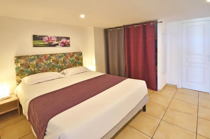 Une chambre lumineuse avec un grand lit recouvert d'une courtepointe.