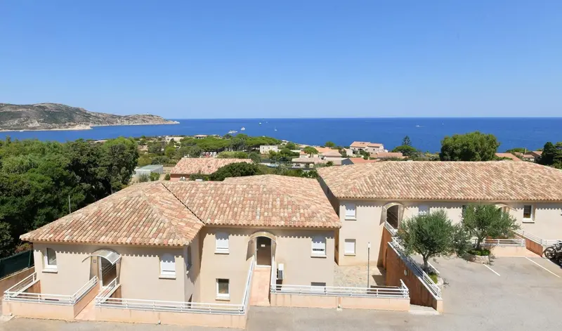 Vue aérienne sur des bâtiments aux toits en tuiles et la mer au loin.