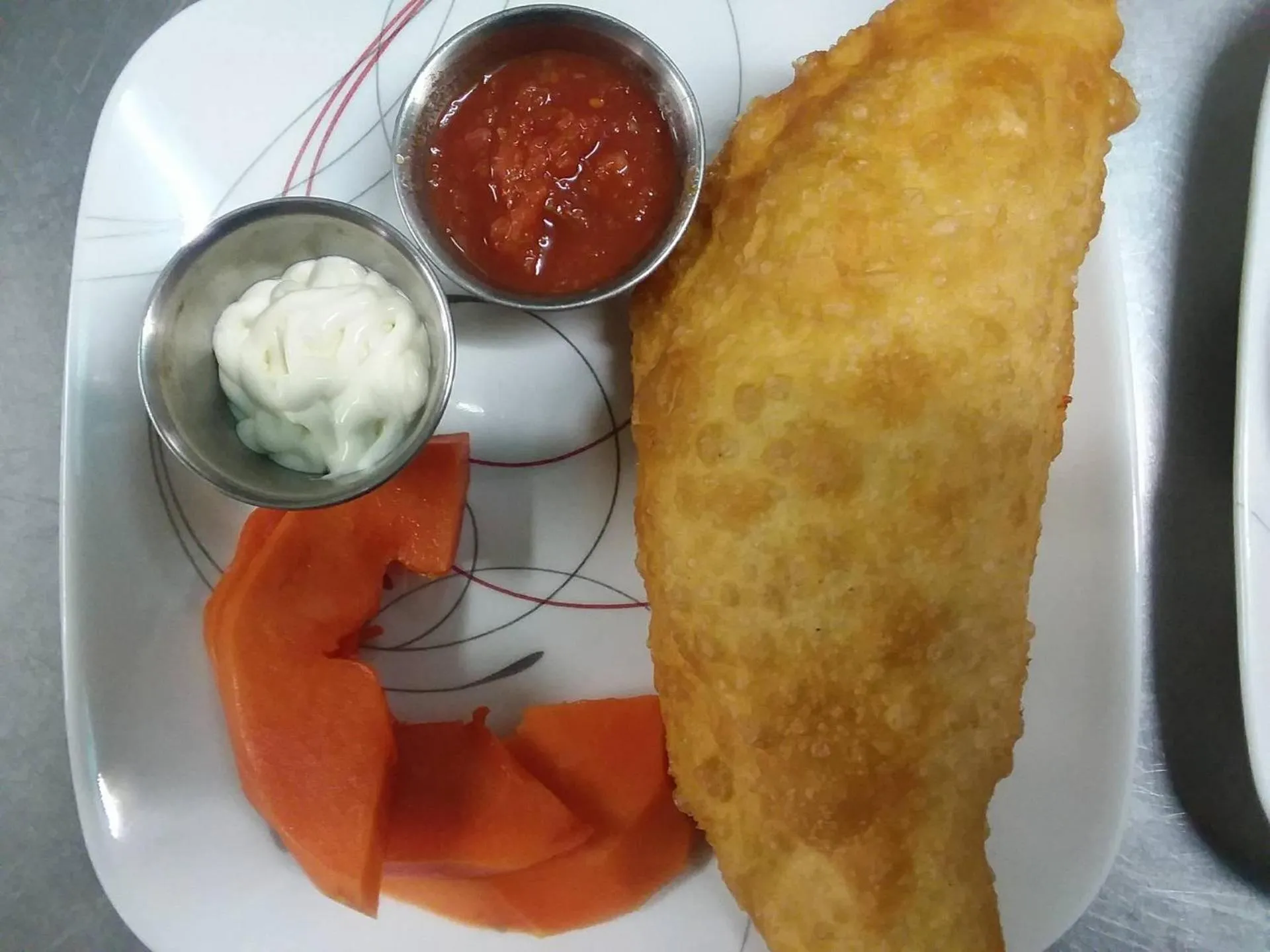 Assiette avec une portion de nourriture accompagnée de sauces et de légumes.