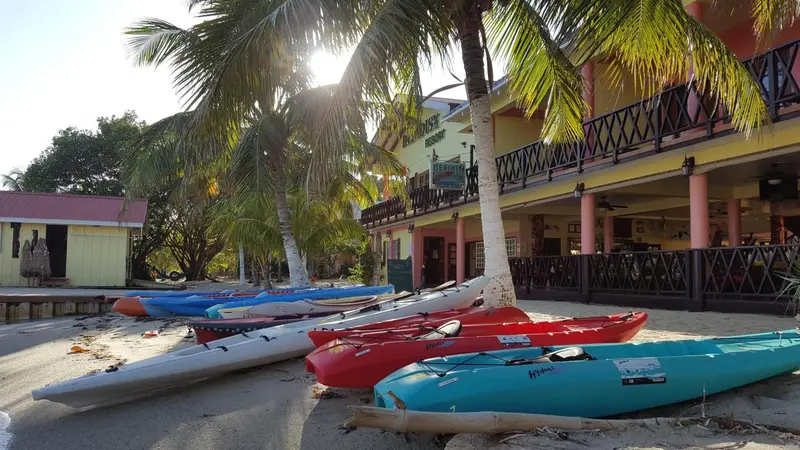 Bâtiment coloré avec des kayaks sur une plage de sable.