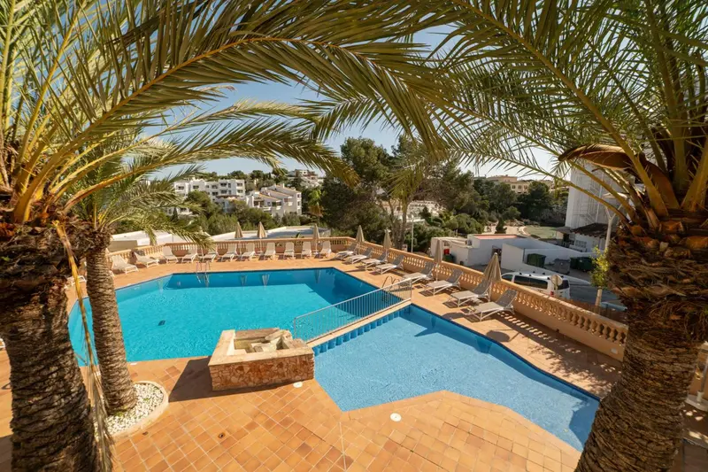 Une piscine rectangulaire entourée d'une terrasse ensoleillée avec des transats.
