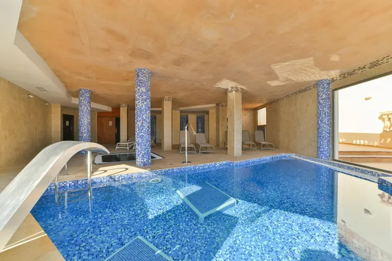 Une piscine intérieure avec des colonnes décoratives et des transats.