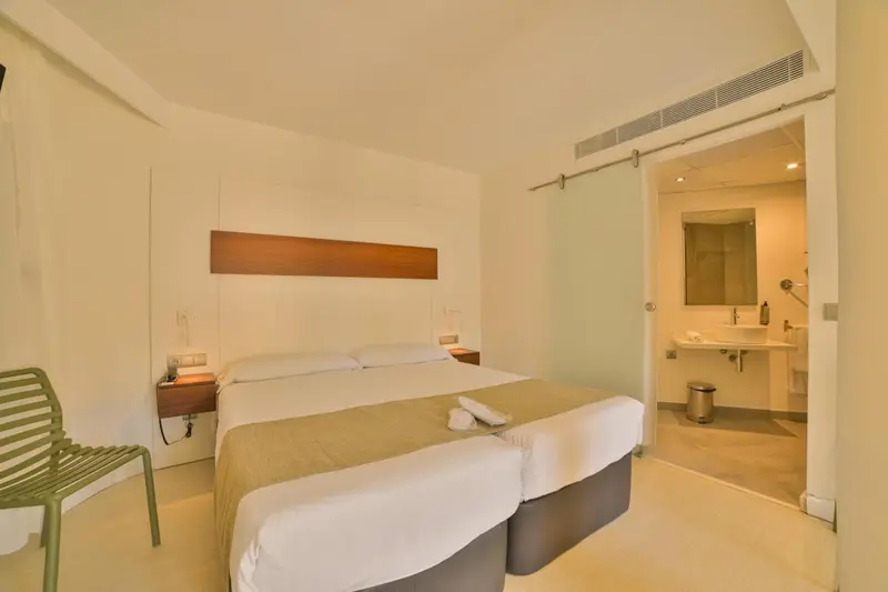 Une chambre lumineuse avec un lit double et un accès à une salle de bain.