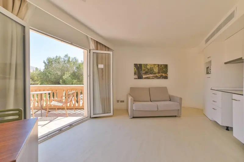 Espace de vie lumineux avec canapé et accès à une terrasse ensoleillée.