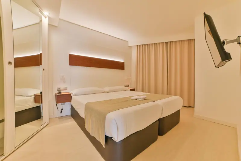 Une chambre lumineuse avec deux lits simples et un grand miroir.