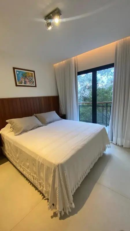 Une chambre lumineuse avec un grand lit recouvert d'une couverture blanche et un accès à une terrasse.