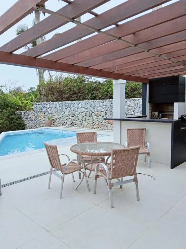 Terrasse carrelée avec mobilier de jardin et barbecue.