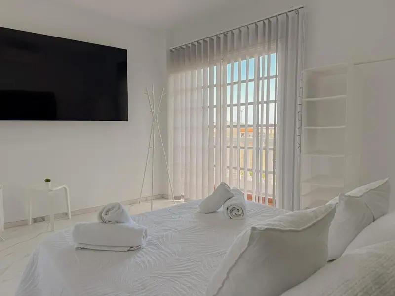 Une chambre lumineuse avec un grand lit recouvert de linge blanc.