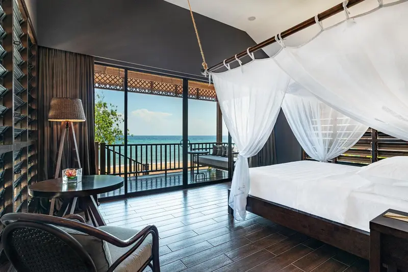Une chambre avec un grand lit à baldaquin donnant sur la mer.