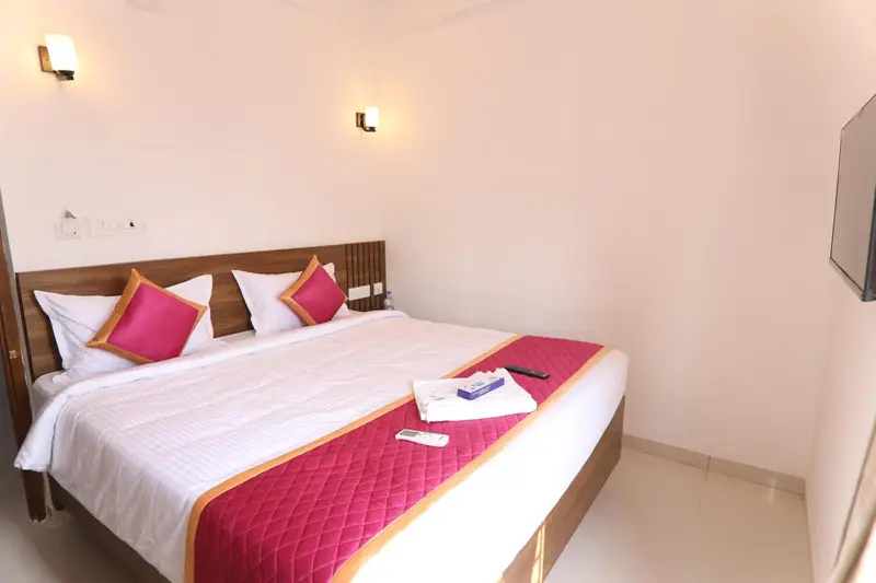 Lit double avec oreillers roses et couverture rouge dans une chambre lumineuse.