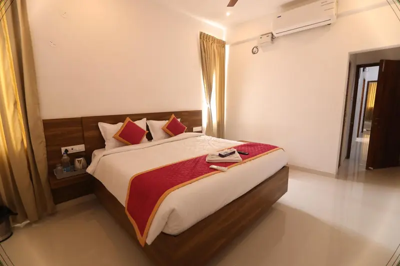 Une chambre lumineuse avec un grand lit recouvert d'une courtepointe rouge et de coussins.