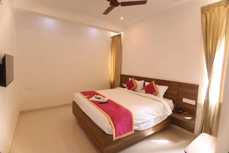 Une chambre lumineuse avec un grand lit recouvert d'une courtepointe colorée.