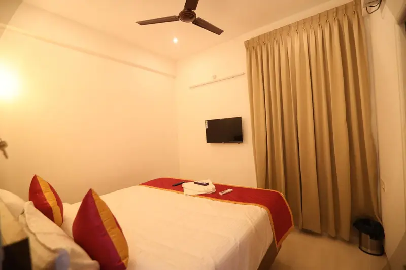 Une chambre lumineuse avec un lit recouvert d'une courtepointe rouge et de coussins.