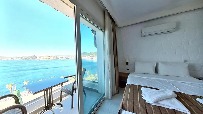 Une chambre lumineuse avec vue sur la mer depuis un balcon.