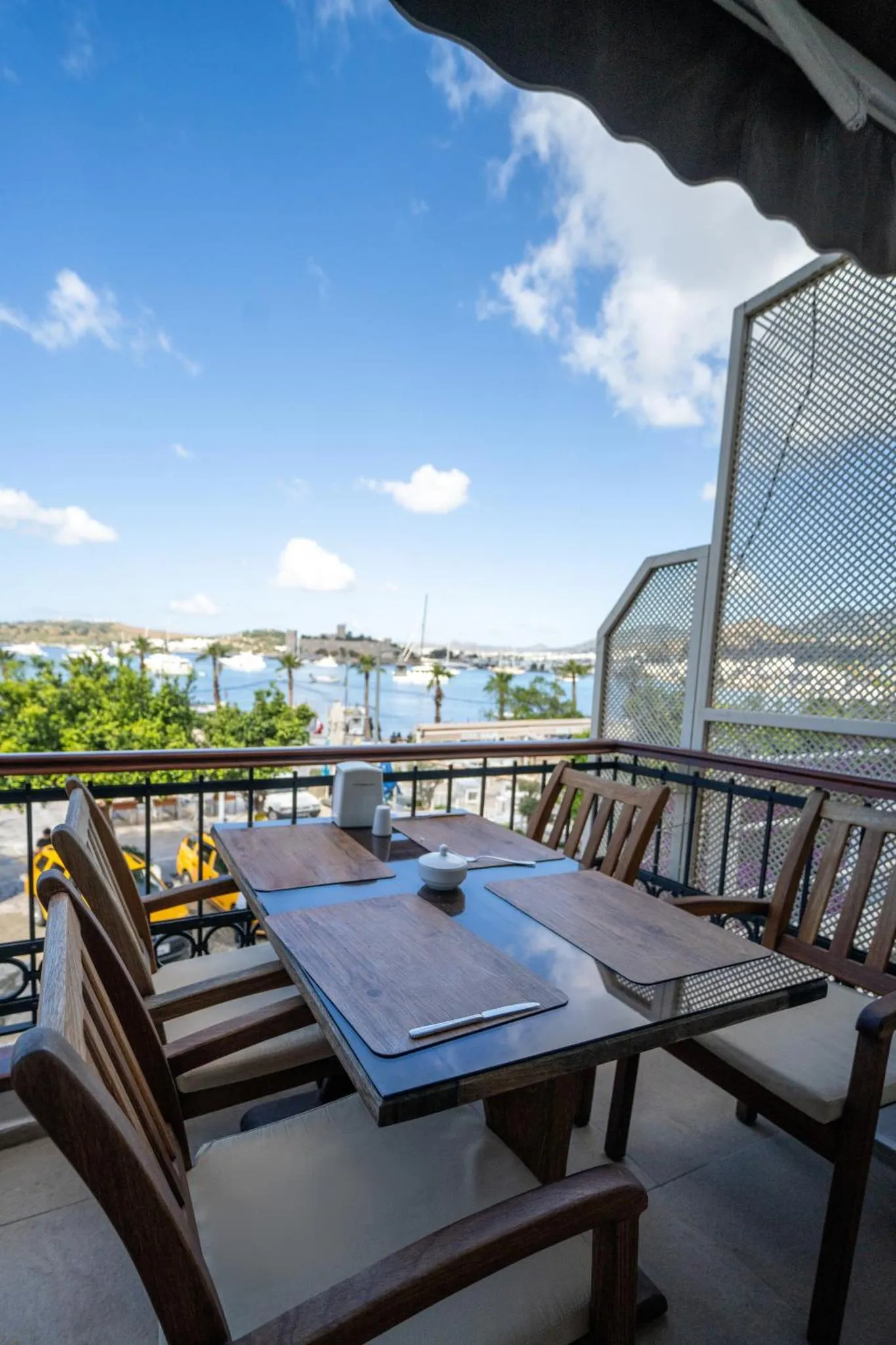 Table dressée sur une terrasse avec vue sur la mer et le port.