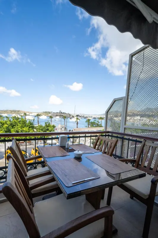 Table dressée sur une terrasse avec vue sur la mer et le port.