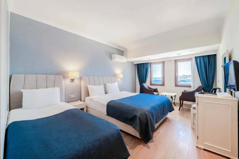 Chambre d'hôtel avec deux lits et une fenêtre donnant sur la mer.