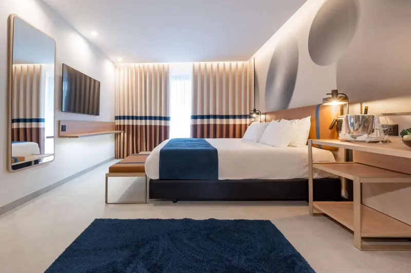 Une chambre moderne avec un grand lit et une télévision murale.