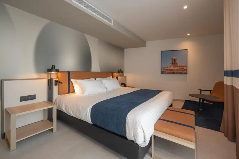 Une chambre moderne avec un grand lit et une décoration sobre.