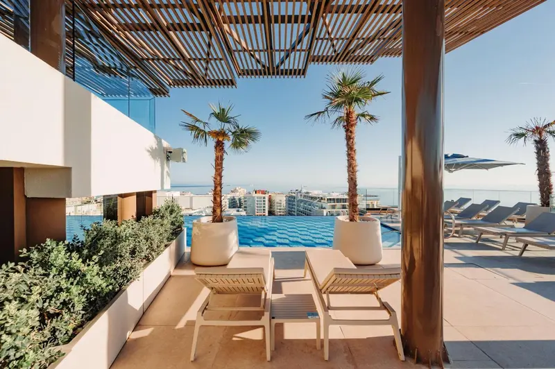 Terrasse avec mobilier de détente surplombant une piscine à débordement.