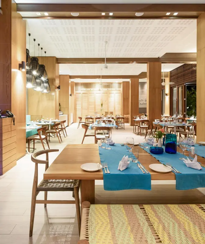 Une salle lumineuse avec des tables dressées pour un repas.